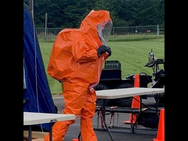 Man in orange hazmat suit walking into a simulation